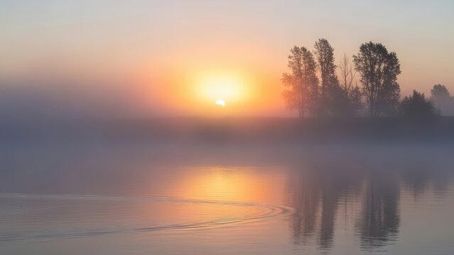 Sun rising over misty river with trees on bank and ripples on water surface creating reflections