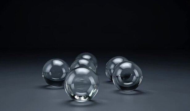 five transparent balls on a dark background. They reflect light and create glare. The balls are close together. The balls move down from top to bottom by jumping