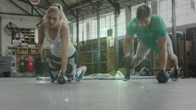 Training pair starting kneeling with dumbbells, alternating rows pressing into push-ups for fitness