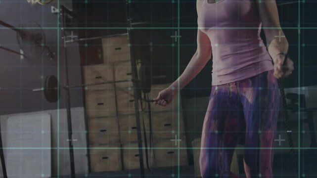 Vertical video: Skipping woman in pink top, leggings keeping pace at gym with jump rope for cardio