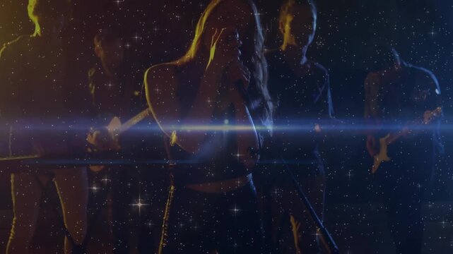Lens flare and glitter sweeping stage, revealing female singer with mic singing while band playing