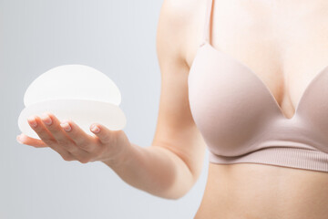 Female adult holding silicone breast implants for cosmetic surgery and enhancement