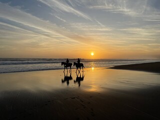 Fototapeta premium Couple Riding Horses on Bali Beach at Sunset