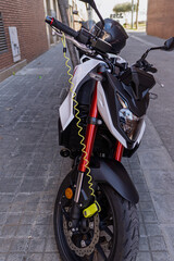 Barcelona, Spain - March 14, 2026: White motorcycle secured with a yellow anti-theft disc lock