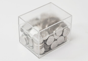 Fototapeta premium Transparent plastic box with coins. Concept of storage, donation, money multiplication.