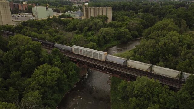 Aerial shot from a drone of the Credit River in the Streetsville area of Mississauga, Ontario, Canada. A freight train crosses a bridge over the waterway.