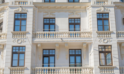 Obraz premium Elegant white facade of a classic building featuring ornate stone carvings, decorative balustrades, and symmetrical windows in a sophisticated architectural style