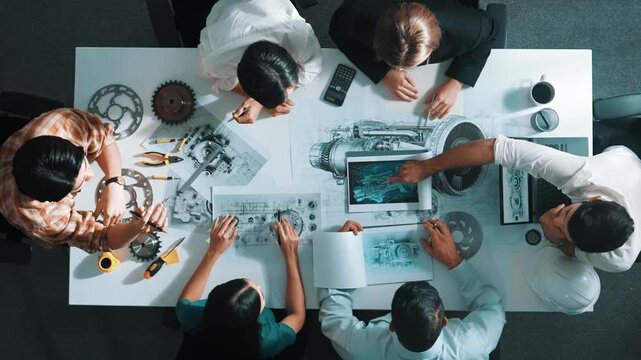 Top view of smart engineer team in casual cloth talking about turbine engine structure at table with metal gear, calculator, sticky notes. Group of technician taking a note in meeting. Alimentation.