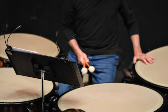 Cropped view of percussionist playing timpani on stage indoors