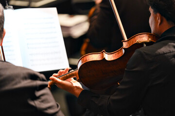 Rear view of violin player in orchestra with sheet music on stage © Moiseii Production