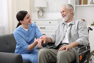 Obraz premium Care worker checking senior man's pulse in wheelchair indoors