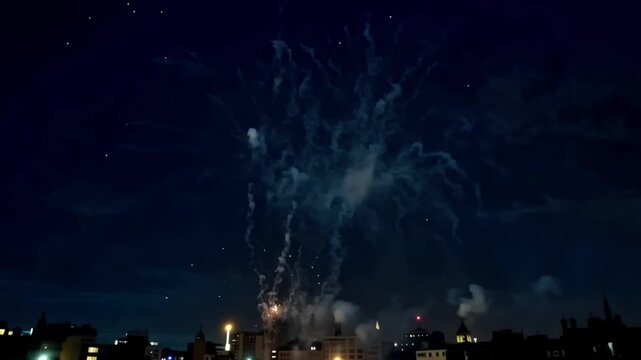 Vibrant blue and gold fireworks exploding over a cityscape at night, with smoke trails and lights in the background, for celebrations