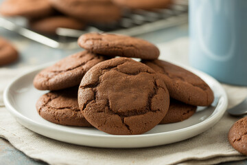 Fototapeta premium Freshly Baked Homemade Chocolate Crinkle Cookies Stacked on White Plate