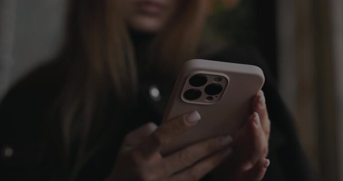 Close up of female hands holding smartphone in a beige case