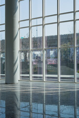 Naklejka premium Modern architectural interior with glass curtain wall and natural light reflections on polished floor