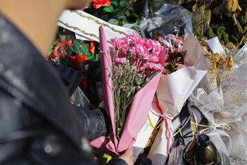 Woman placing flower bouquet on grave at cemetery. Commemoration and remembrance moment during...