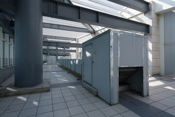 Industrial factory corridor with metal enclosures and equipment installations under steel framework