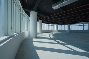 Obraz premium Modern spacious office interior with curved floor-to-ceiling windows and exposed structural elements