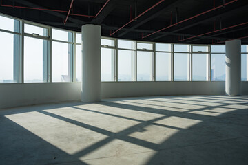 Obraz premium Empty modern office interior with floor-to-ceiling windows and natural light casting geometric shadows