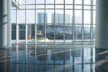 Obraz premium Modern architectural interior with glass curtain wall reflecting light and shadows on polished marble floor