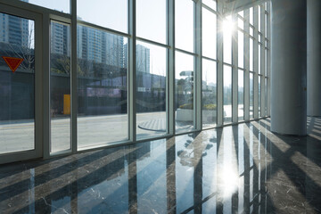 Obraz premium Modern office building lobby with glass curtain wall and sunlight streaming through