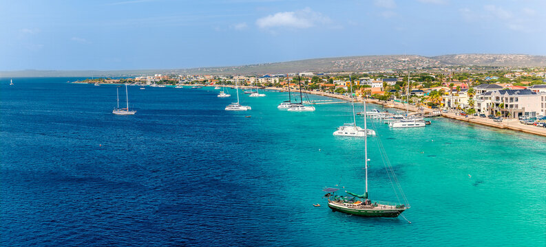 A panorama view of boats moored off the coast in Kralendijk in Bonaire on a bright day