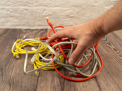 Hand reaching into tangled mess of ethernet network cables