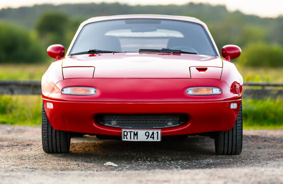 Gothenburg, Sweden - July 25 2024: Front view of red 1990 Mazda MX5 sports car parked on quiet rural road.