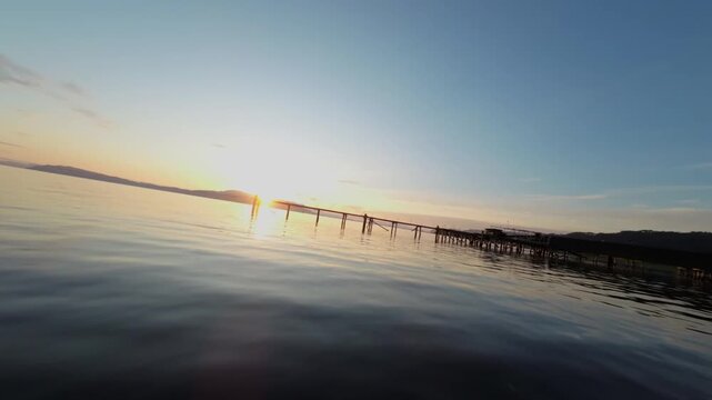 FPV Drone Flight Over WaterTowards Abandoned Wooden Per at Sunset