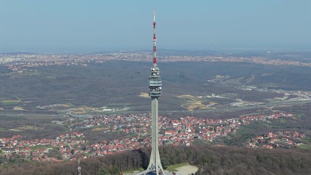 Aerial drone orbiting shot around the Avala telecommunication tower in Belgrade, Serbia, with a vast landscape and highway in the background.