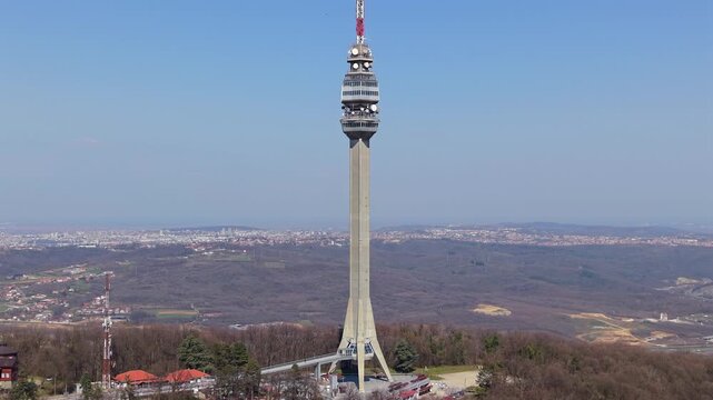 Aerial drone tilt up shot of the Avala telecommunication tower in Belgrade, Serbia, revealing a panoramic city landscape.
