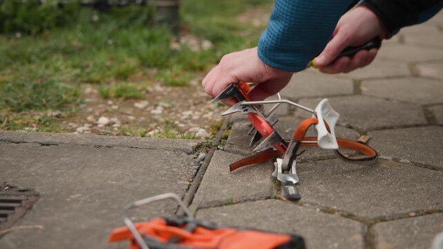 A climber meticulously sharpens the front points of their ice climbing crampons with a handheld file. This essential maintenance ensures maximum bite into hard ice during a winter ascent.