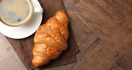 Fototapeta premium Puff pastry. Tasty fresh croissant and cup of coffee on wooden table, top view. Space for text