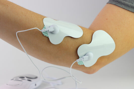 Electrodes attached to arm for TENS therapy, promoting muscle relaxation and pain relief
