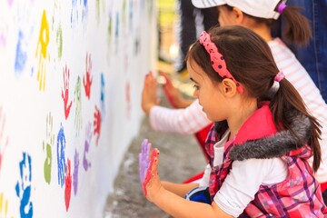 Fototapeta premium Child Pressing Colorful Handprint on White Wall Outdoor