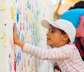 Girl Making Colorful Handprints on White Wall Outdoor © alozar