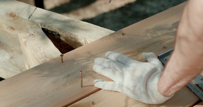 man using electric drill to screw into wooden deck