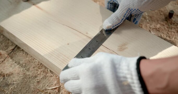 carpenter marking wooden plank with ruler and pencil