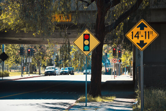 Yellow traffic signs warn of height restrictions and traffic signals ahead