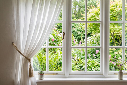 White sheer curtain on sunlit mullioned window with garden view