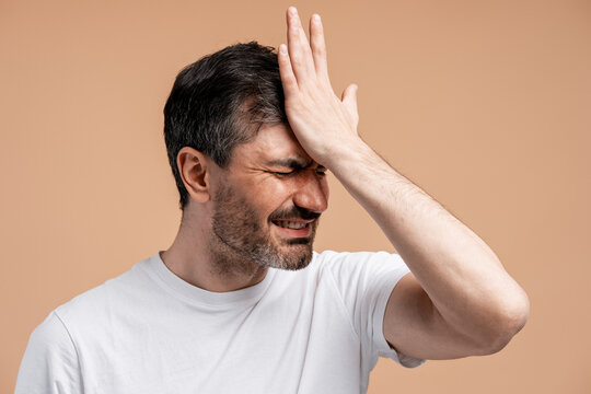Frustrated man making facepalm gesture, expressing regret and disappointment