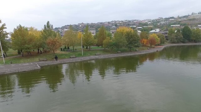 autumn, park, lake, water, reflection, trees, yellow, green, foliage, leaves, season, nature, landscape, calm, peaceful, overcast, cloudy, city, town, houses, hillside, walkway, promenade, people, wal