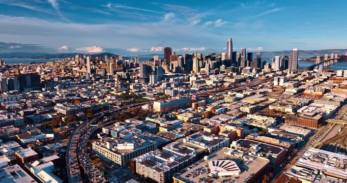 Rising over the vast cityscape of San Francisco, California, USA on sunny day. Multiple cars move by the roads to and from the Oakland Bay Bridge.