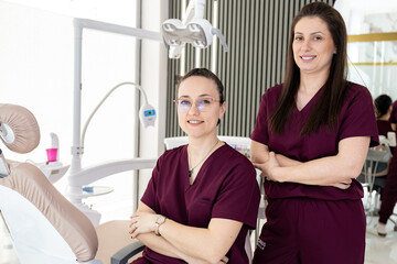 Obraz premium Dentists stand together in modern clinic with dental chairs and equipment in background