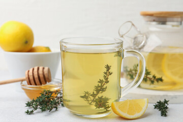 Naklejka premium Fresh thyme tea in glass cup, honey and slice of lemon on grey table, closeup