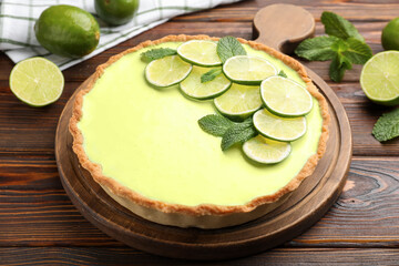 Tasty lime pie with fruit slices and mint leaves on wooden table, closeup © New Africa