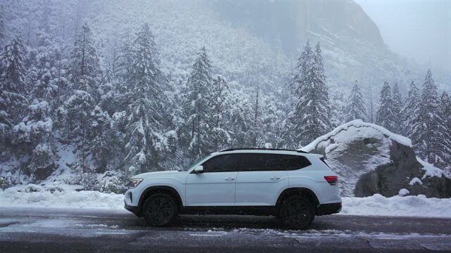 White suv parked on snowy roadside yosemite valley backdrop towering snowladen pines granite boulder beside road misty mountain icy asphalt quiet winter atmosphere traveler pause cinematic