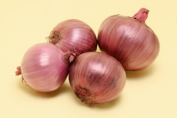 Four red onions on a pale yellow background, studio-lit, simple composition, smooth skins and visible root ends