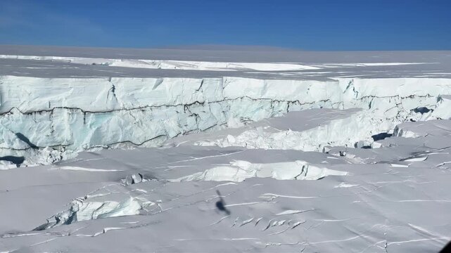 Majestic Antarctic ice shelf with deep crevasses under a clear blue sky