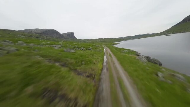 Cinematic Drone Tracking Shot of a Dirt Road Along a ake in Green Highlands
